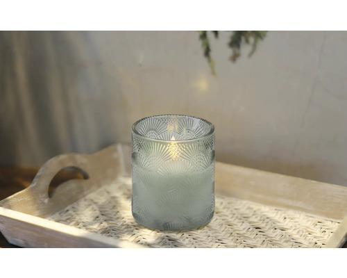 Dekorativt ljus i ett dekorerat glas på en bricka