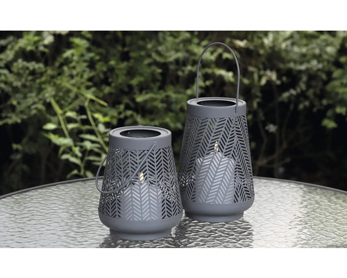 Två grå lyktor med mönster på ett bord