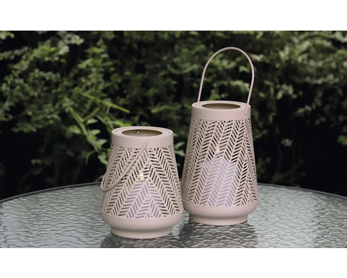 Två dekorativa lyktor med handtag och geometriskt mönster står på ett bord.