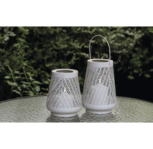 Två vita lyktor med mönster på ett bord