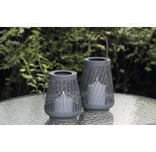 Två dekorativa lyktor med ljus på ett bord utomhus.