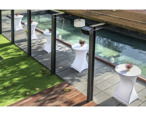 Terrass med ståbord, växter och en liten damm