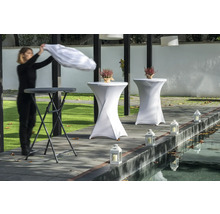 Scen med ståbord, bordsöverdrag, lyktor och en person som lägger på en duk.