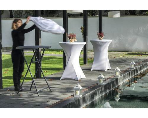 Scen med ståbord, bordsöverdrag, lyktor och en person som lägger på en duk.