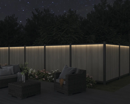 Terrass med upplyst staket och sittgrupp på natten