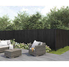 Trädgårdsscen med mörk insynsskydd, loungemöbler och planteringar