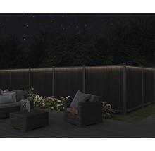 Trädgårdsmöbler på en terrass med upplyst staket i mörkret