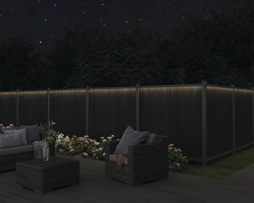 Trädgårdsmöbler på en terrass med upplyst staket i mörkret