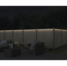 Trädgård med upplyst staket, sittgrupp och blommor på natten