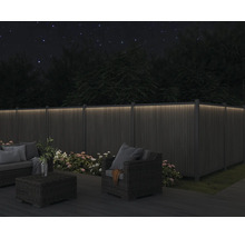 Upplyst trädgårdsstaket med trädgårdsmöbler på natten