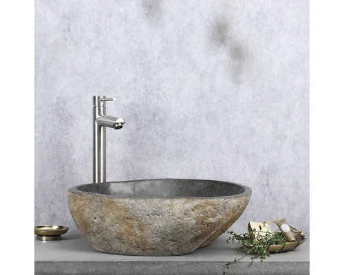 Tvättställ i natursten med armatur på hylla med tvålkopp och dekoration