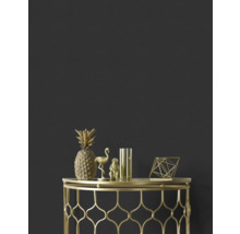 Dekorativ ananas, flamingo, apa, vas och geometrisk figur i guld på ett sidobord i guld mot en mörk vägg.