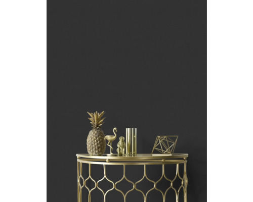 Dekorativ ananas, flamingo, apa, vas och geometrisk figur i guld på ett sidobord i guld mot en mörk vägg.