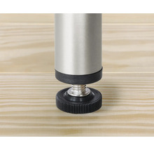 Detaljvy av ett justerbart möbelben i metall och plast på en träyta.