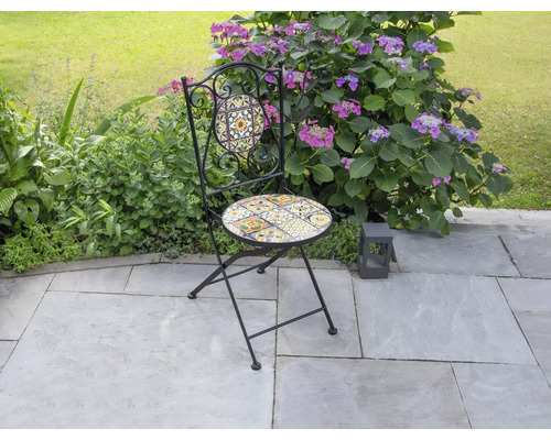 Trädgårdsscen med en fällstol med mosaikmönster