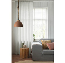 Vardagsrum med soffa, sidobord av trä, gardin och hänglampa