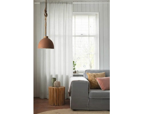 Vardagsrum med soffa, sidobord av trä, gardin och hänglampa