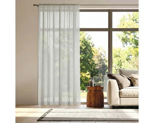 Vardagsrum med gardin framför fönstret, soffa och matta