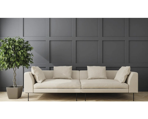 Ljus soffa med kuddar och krukväxt framför en väggpanel