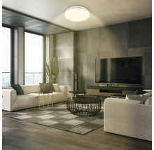 Vardagsrum med taklampa, soffa och TV för en ljus och modern atmosfär.