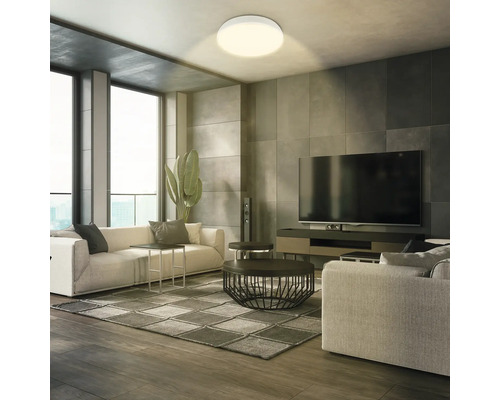 Vardagsrum med taklampa, soffa och TV för en ljus och modern atmosfär.