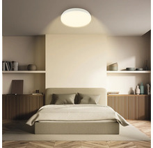 Sovrum med dubbelsäng, trägolv och rund taklampa.