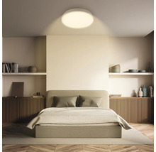 Sovrum med dubbelsäng, hyllor och rund taklampa.