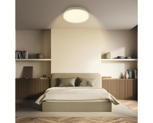 Sovrum med dubbelsäng, hyllor och rund taklampa.