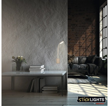 Vardagsrum med vägglampa ovanför bord med böcker och blommor