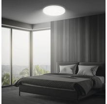 Sovrum med säng, stort fönster och rund taklampa