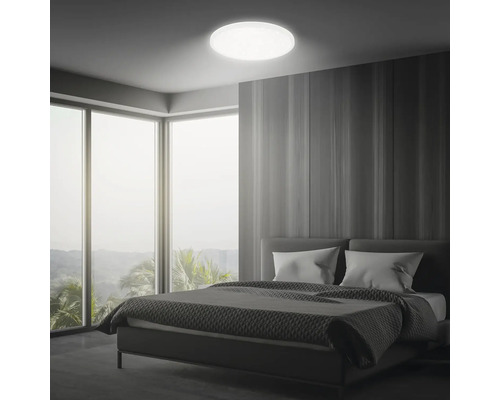 Sovrum med säng, stort fönster och rund taklampa