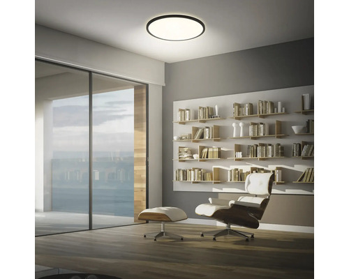 Vardagsrum med taklampa, hyllor och fåtölj