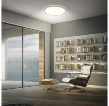 Ljust vardagsrum med taklampa, bokhylla och fåtölj