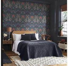 Sovrum med mönstrade tapeter, säng med sänggavel i rotting och dekorativ matta