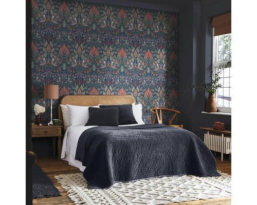 Sovrum med mönstrade tapeter, säng med sänggavel i rotting och dekorativ matta