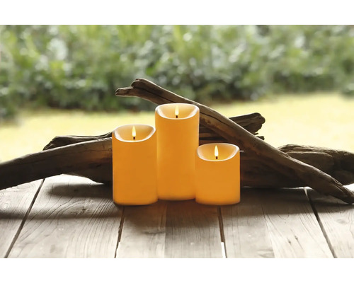 Tre dekorativa ljus med elektronisk lågeffekt på ett träbord