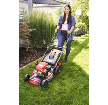 Kvinna skjuter en gräsklippare i trädgården.