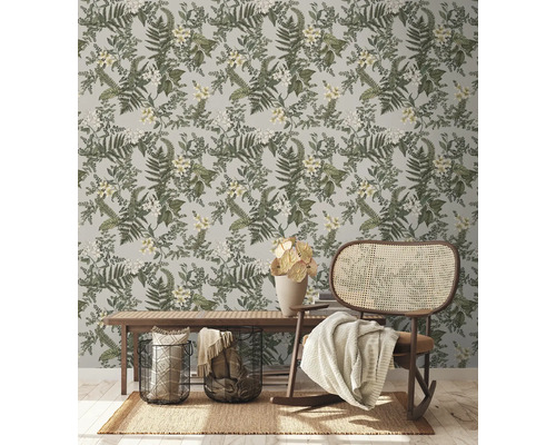 Dekorativt rum med botanisk tapet, bänk och rottinggungstol.