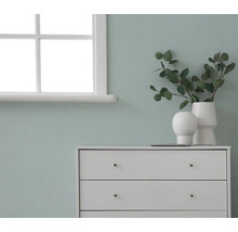 Byrå med dekorationer framför en vägg bredvid ett fönster