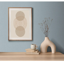 Dekorativt stilleben med inramat konsttryck, böcker, kopp och vas på ett bord