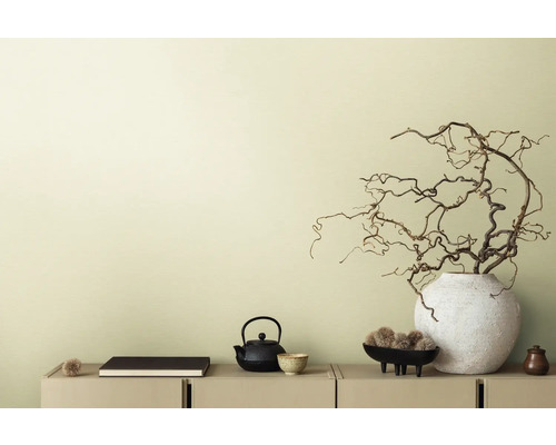 Dekorativ scen med tekanna, bok och grenar i vas på en skänk