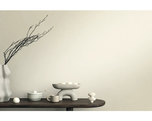 Dekorativ scen med vas, grenar, skål och keramiska figurer på ett bord