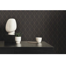 Dekorativ scen med geometrisk tapet, skulpturalt huvud, växt och skål på ett bord