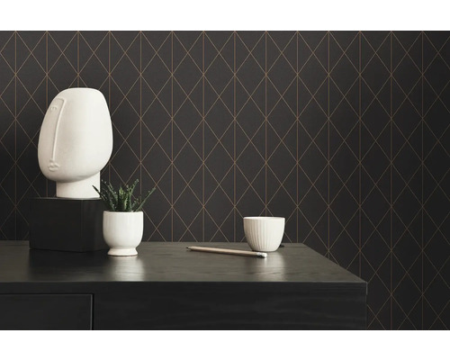 Dekorativ scen med geometrisk tapet, skulpturalt huvud, växt och skål på ett bord