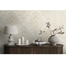 Scen med mönstrad tapet, lampa, ljus och dekorativ vas på en byrå