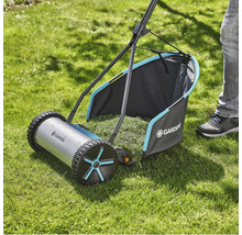 Handgräsklippare på gräsmatta med gräsuppsamlare