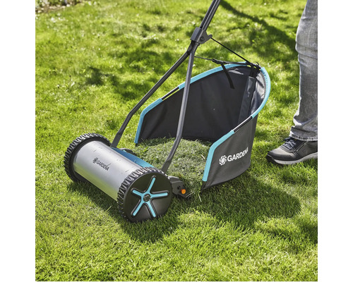 Handgräsklippare på gräsmatta med gräsuppsamlare