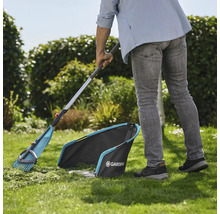 Trädgårdsscen med trädgårdsmästare som sopar gräsmattan med en lövräfsa och en gräsuppsamlare från Gardena