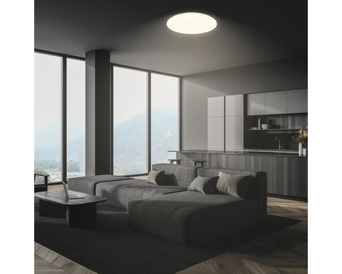 Vardagsrum med soffa, kök och taklampa