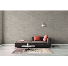 Vardagsrum med soffa, matta, bord och golvlampa framför en strukturtapet.